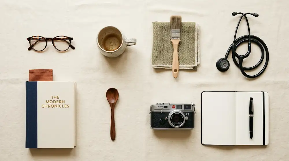 Modern editorial flat-lay of profession-symbol objects on a cream surface, representing the components of identity capital.